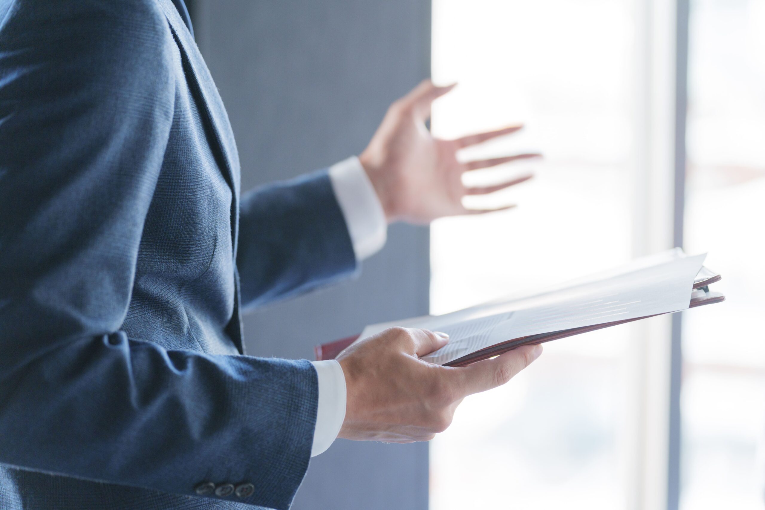 会議で紙資料を見てプレゼンテーションする男性